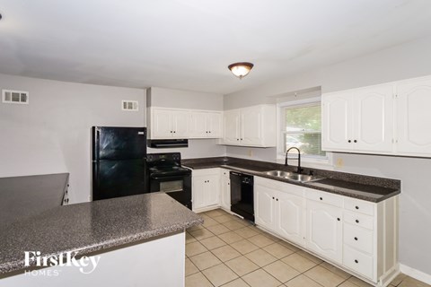 A kitchen with white cabinets and a black fridge.