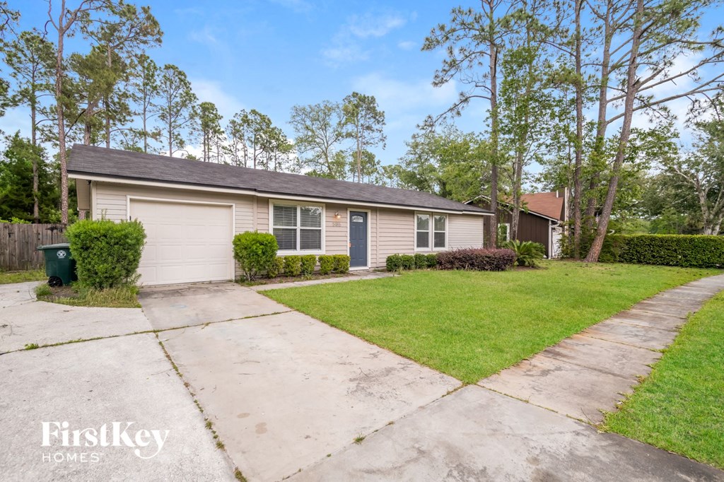a beige house with a driveway and a lawn