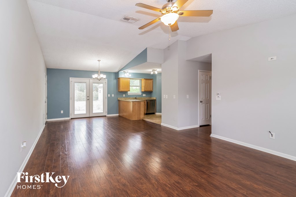 the living room and kitchen of an empty house with a ceiling fan