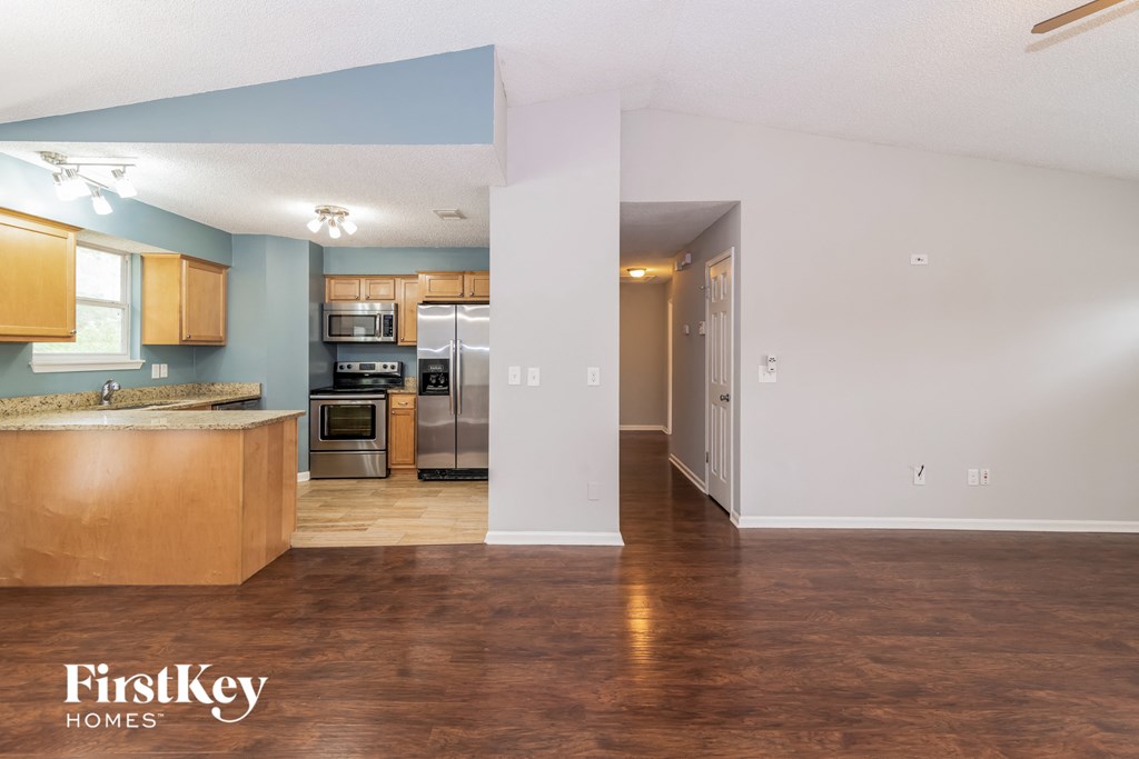 an empty kitchen with wood flooring and stainless steel appliances