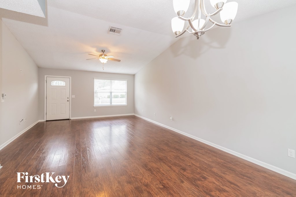 the living room of an empty house with wood flooring and a ceiling fan