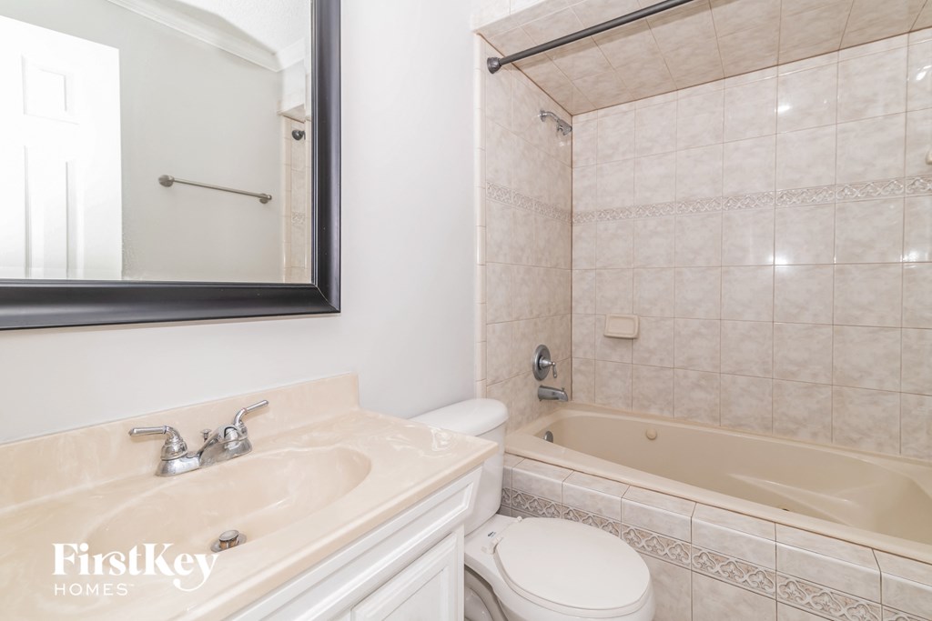 a white bathroom with a tub and a sink and a mirror