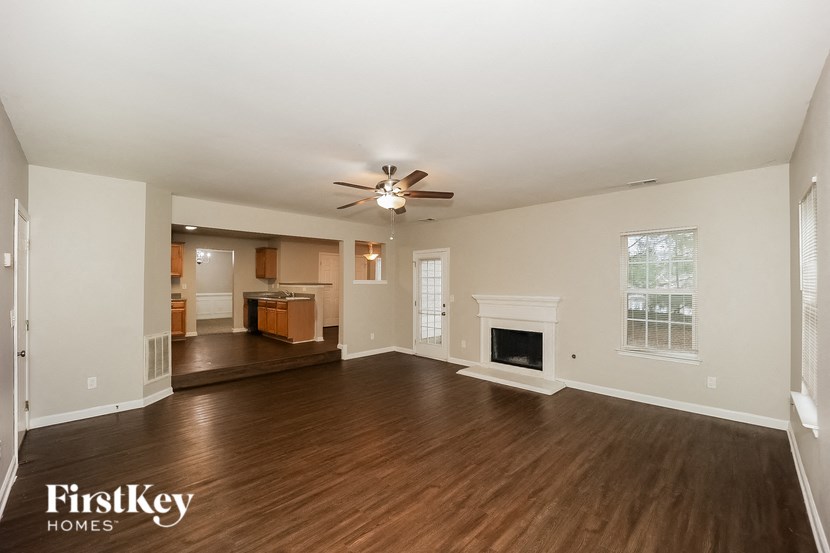 an empty living room with a ceiling fan and a fireplace