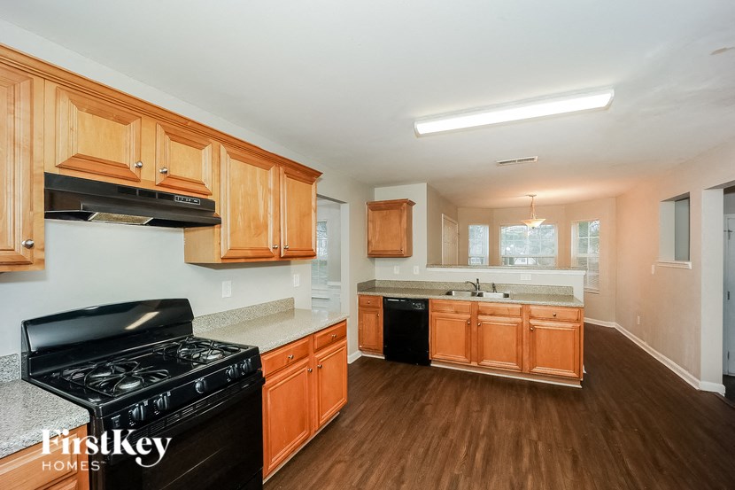 a kitchen with wood flooring and wooden cabinets and black appliances