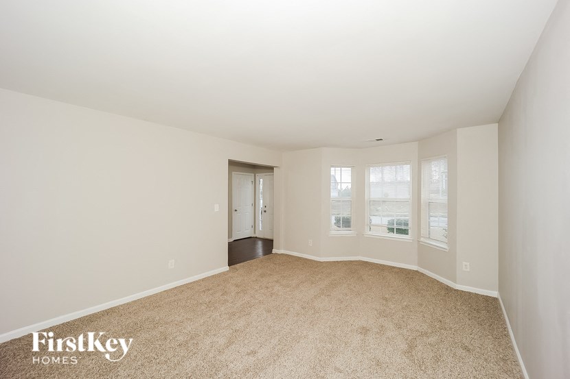 a spacious living room with carpet and a door to a hallway
