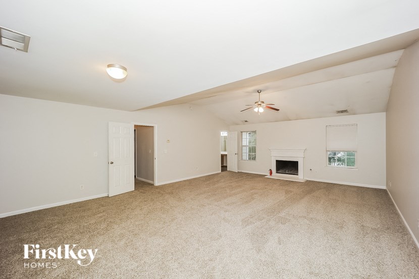 an empty living room with a fireplace and a ceiling fan