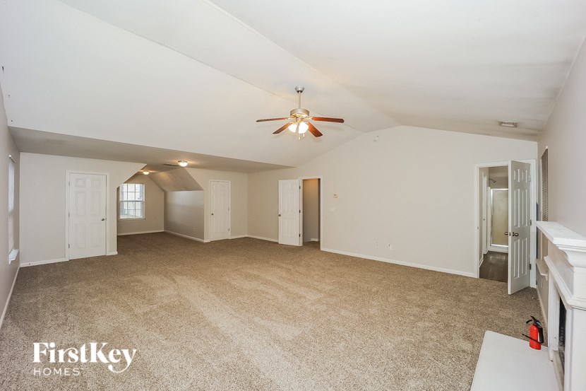 an empty living room with a ceiling fan and white walls