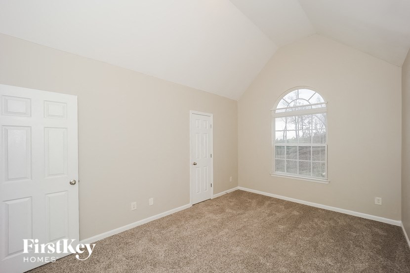 a bedroom with carpet and a door and a window