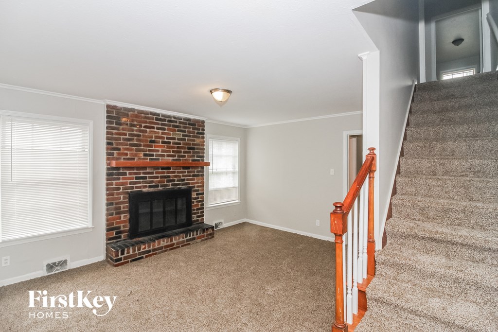 A living room with a fireplace and a staircase.