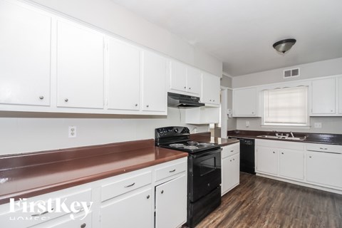 A kitchen with white cabinets and a black stove top oven.