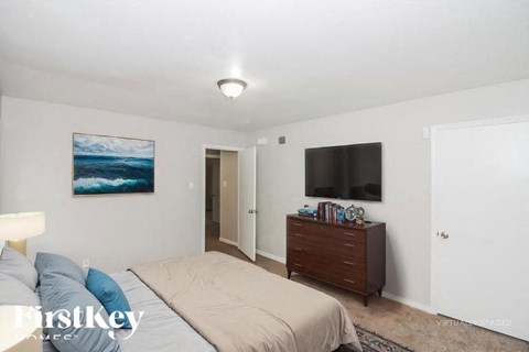 A bedroom with a bed, dresser, and painting on the wall.