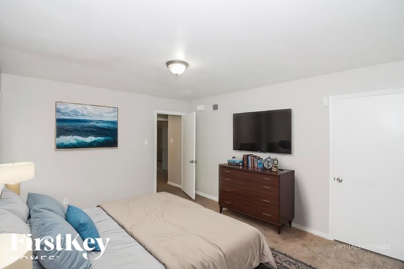 A bedroom with a bed, dresser, and painting on the wall.