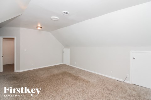 A spacious room with a carpeted floor and white walls.