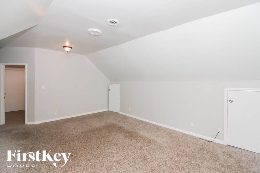 A spacious room with a carpeted floor and white walls.