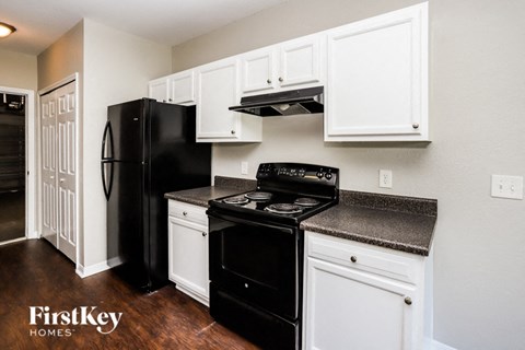 A black refrigerator and stove in a kitchen with white cabinets.
