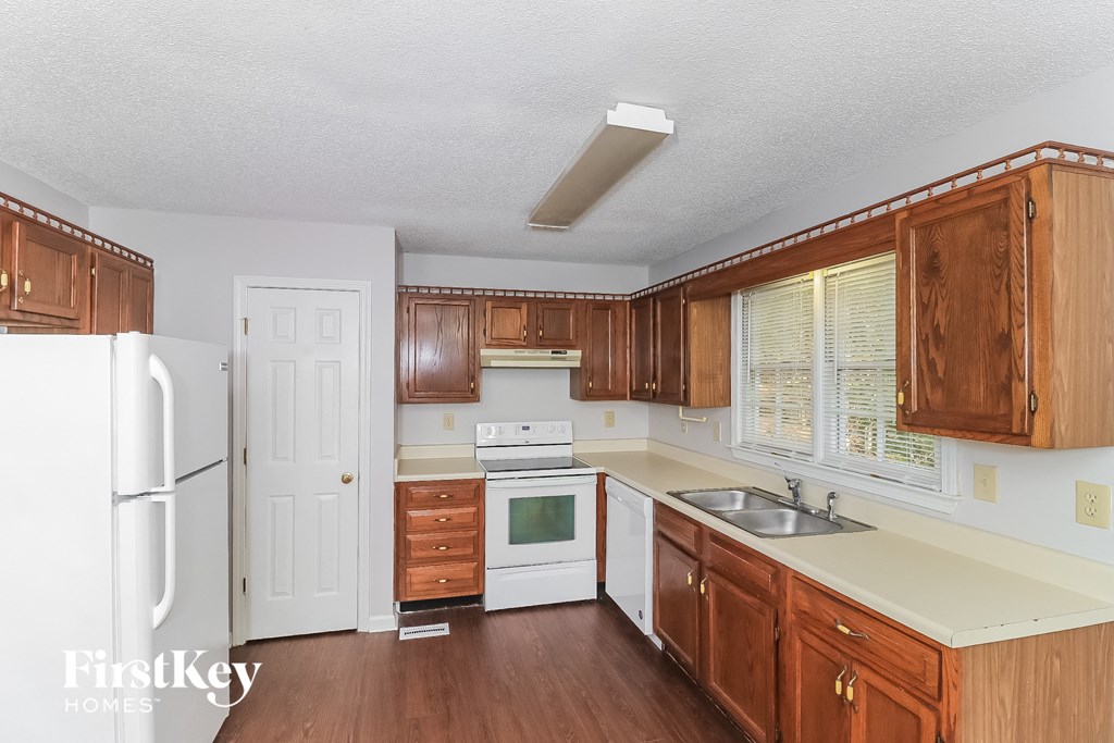 a kitchen with wooden cabinets and white appliances and a refrigerator
