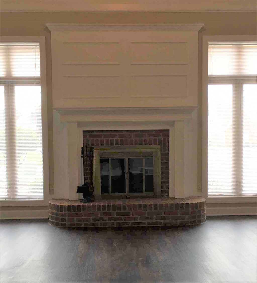 A fireplace with a brick base and a white mantle.