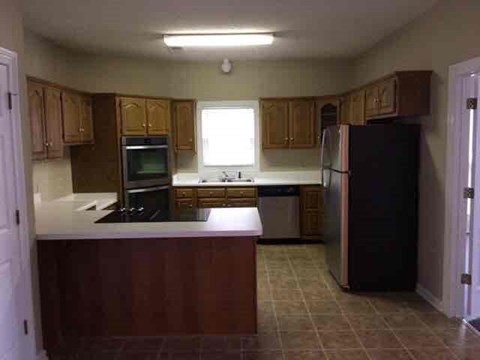 A kitchen with wooden cabinets and a black refrigerator.