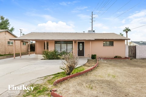 a small pink house with a driveway in front of it