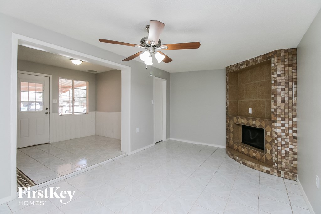 an empty living room with a fireplace and a ceiling fan