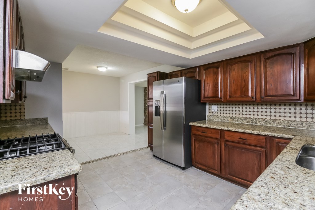 a kitchen with granite counter tops and a stainless steel refrigerator