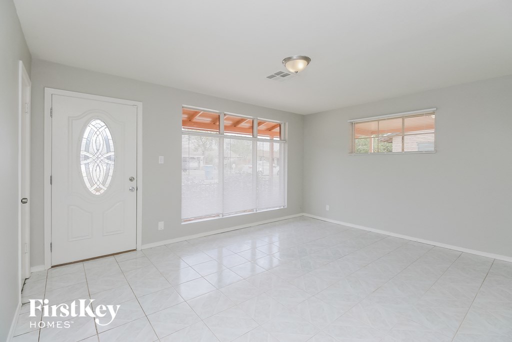 an empty living room with a white tile floor and a white door and window