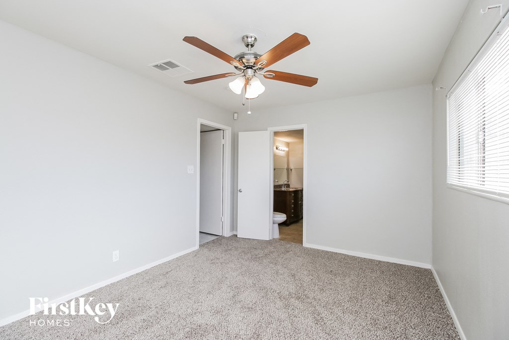 a spacious living room with a ceiling fan and white walls