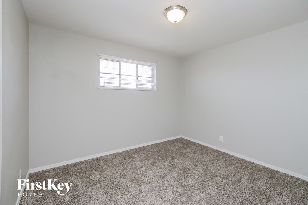 a bedroom with white walls and carpet and a window