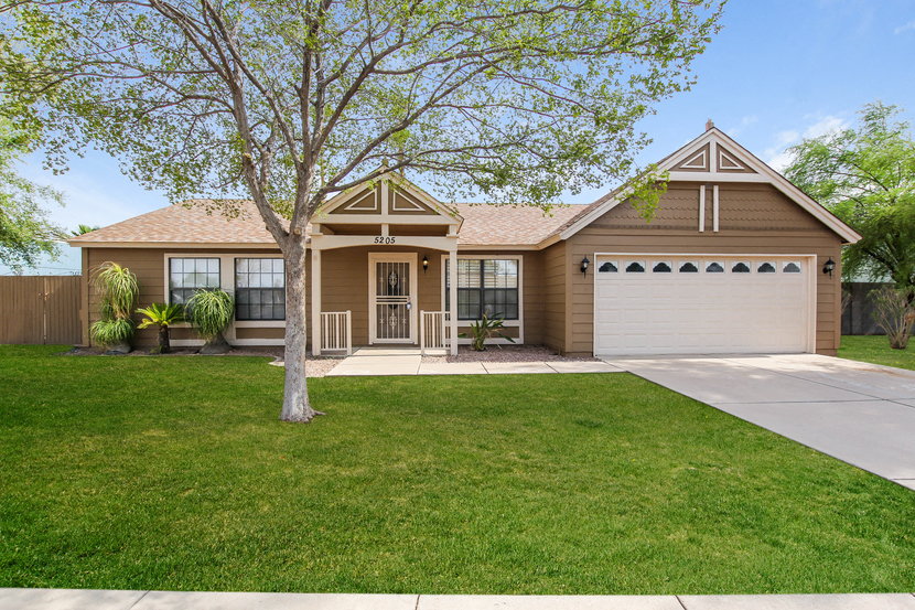 a tan house with a white garage door and a lawn