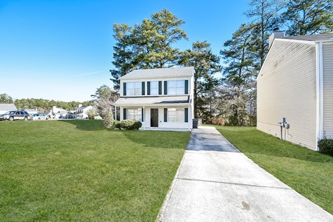 A modern house with a concrete walkway leading to the front door.