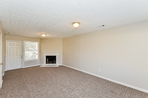 A room with a fireplace and carpeted floor.