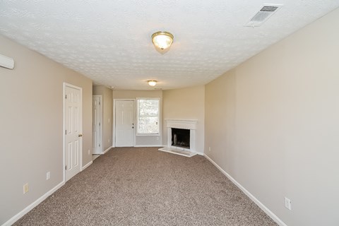 A room with a fireplace and carpeted floor.