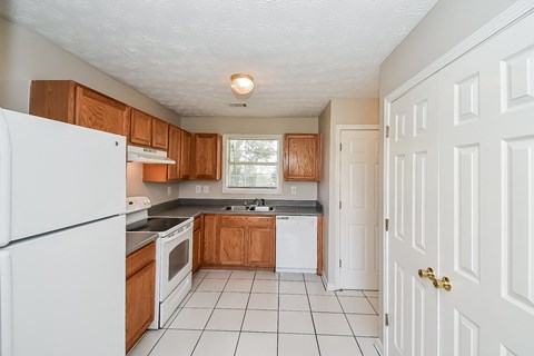 A kitchen with white appliances and wooden cabinets.