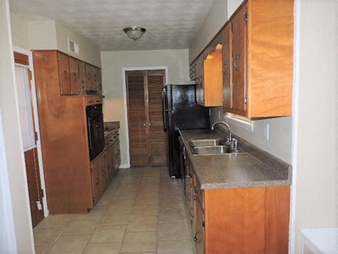 A kitchen with wooden cabinets and black appliances.
