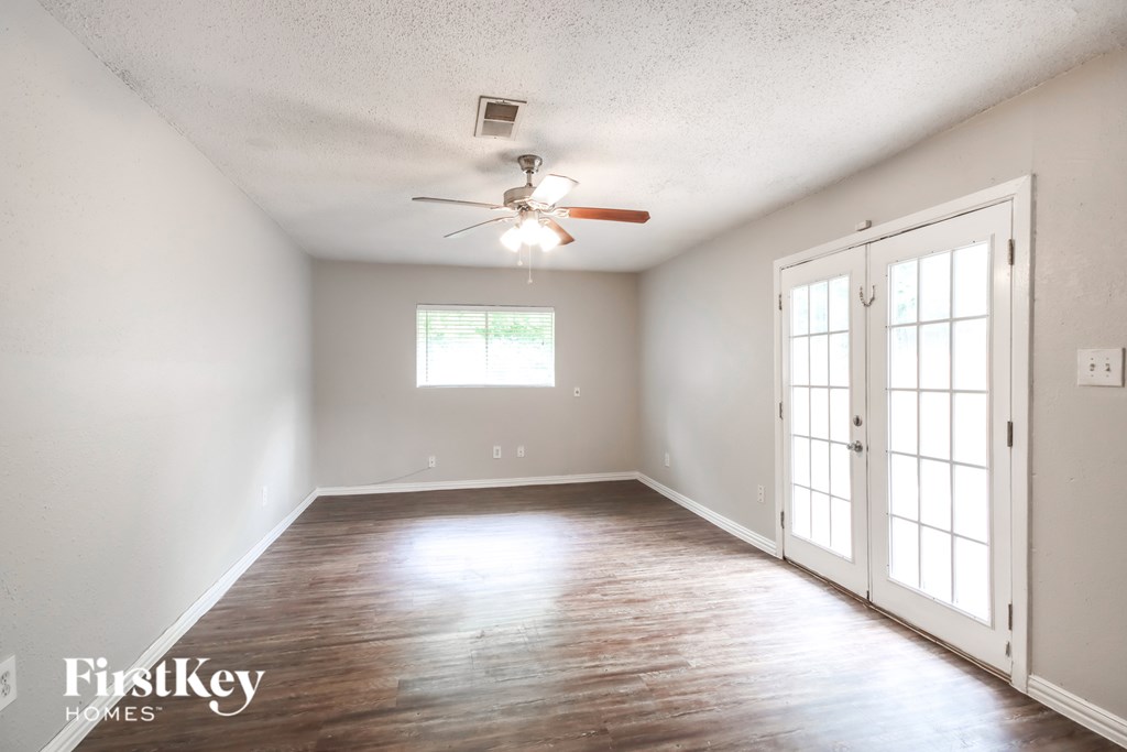 A room with a ceiling fan and sliding glass doors.