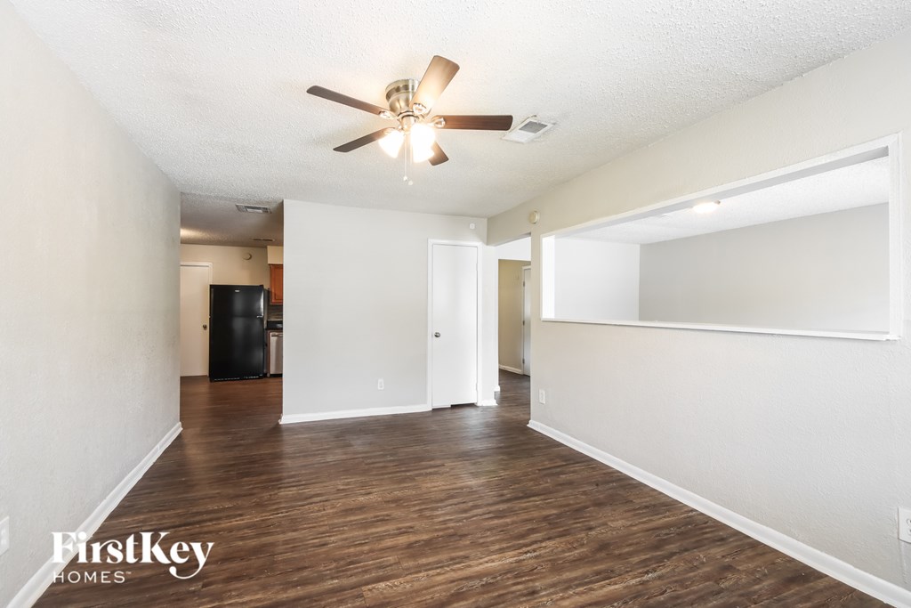 A spacious room with a ceiling fan and wooden flooring.