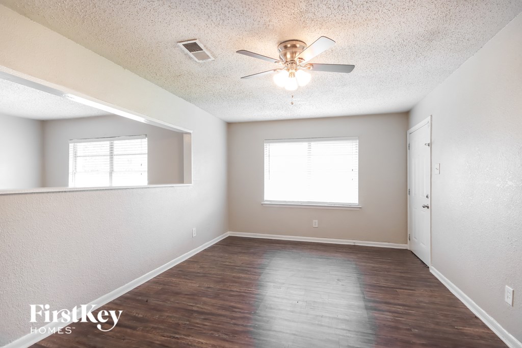 A room with a ceiling fan and two windows.
