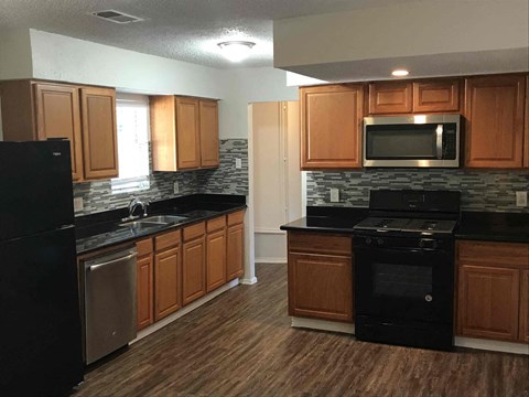 A kitchen with wooden cabinets and black appliances.