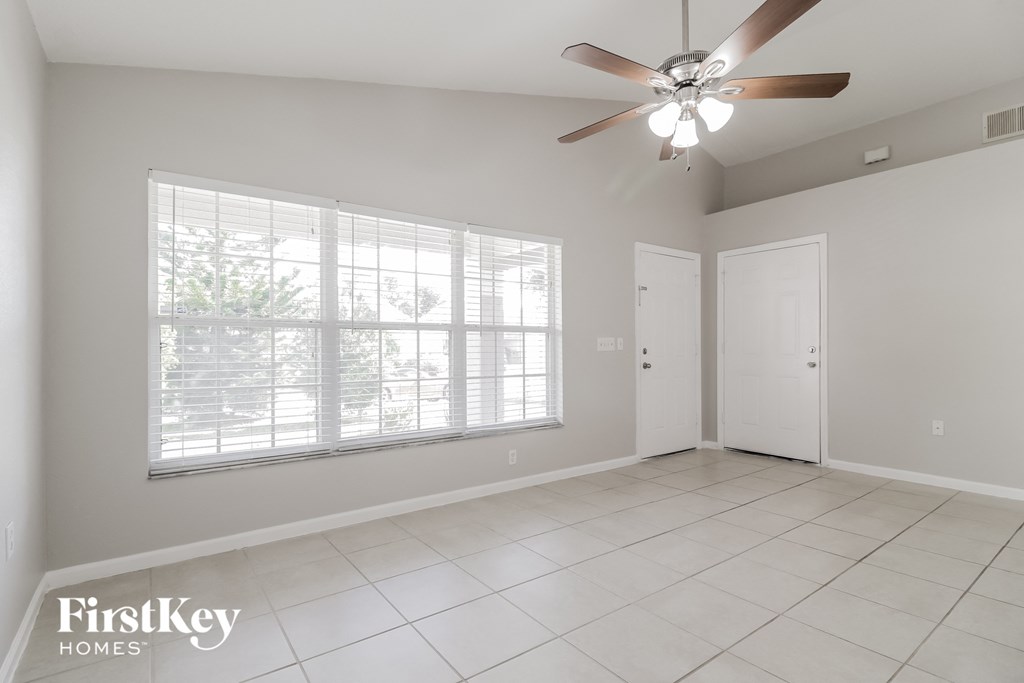 A room with a ceiling fan and a window with blinds.