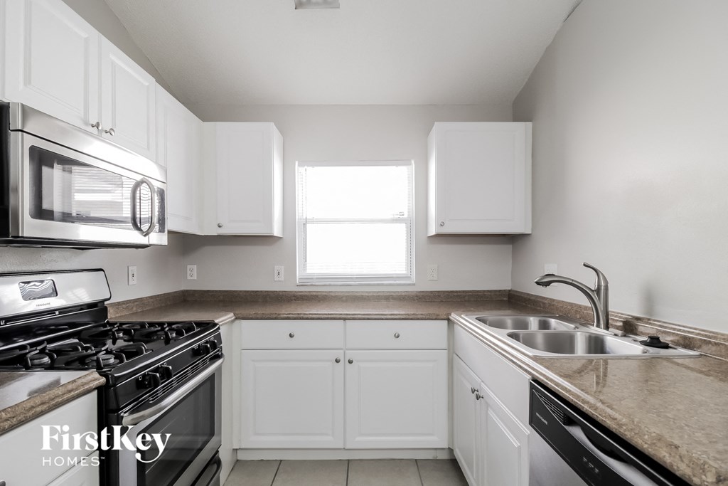 A kitchen with white cabinets and a granite countertop.