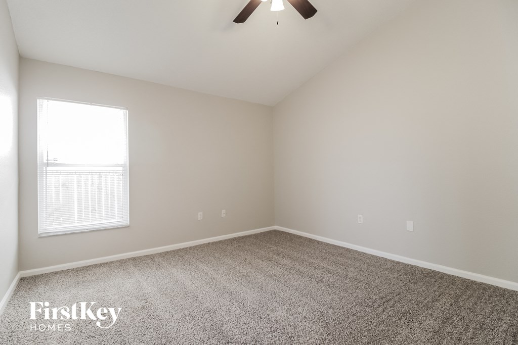 A room with a carpet floor and a ceiling fan.