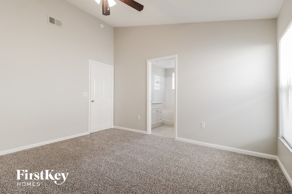 A spacious room with a carpeted floor and a ceiling fan.