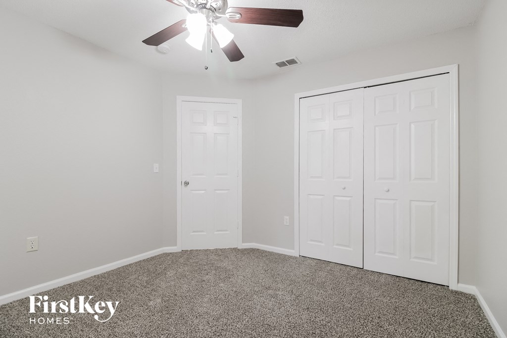 A room with a ceiling fan and two doors.