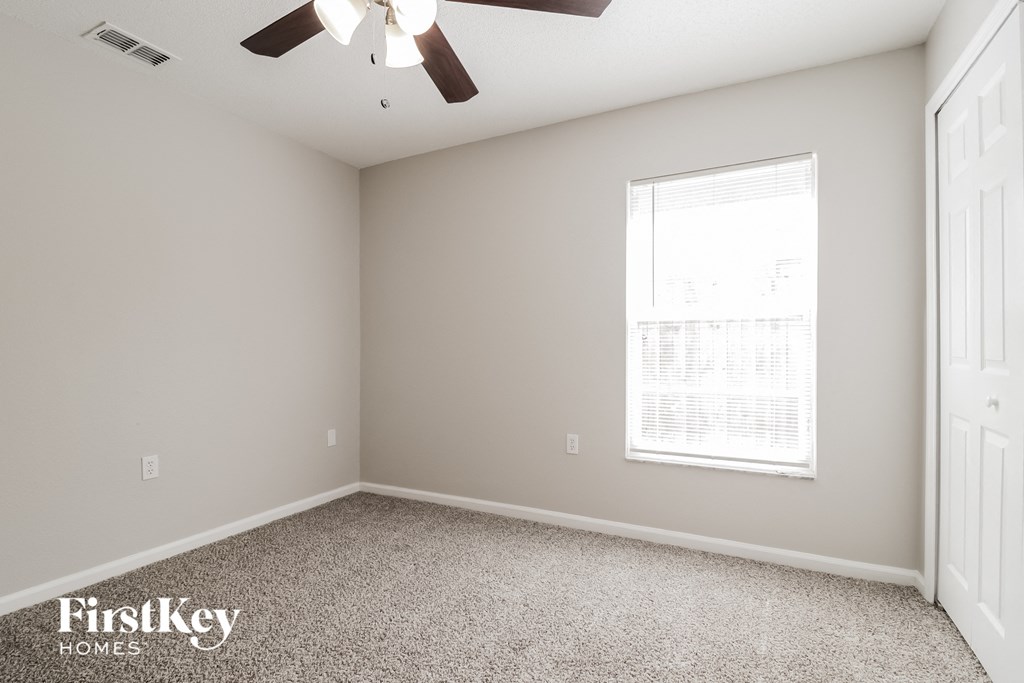 A room with a ceiling fan and a window with blinds.