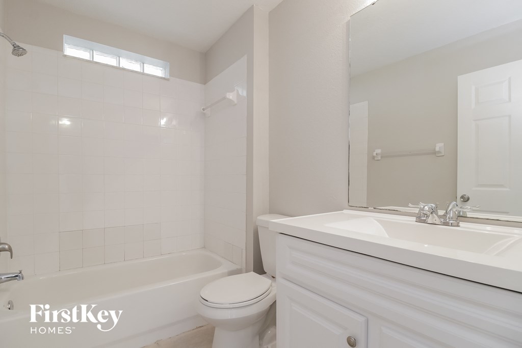 A white bathroom with a tub, toilet and sink.