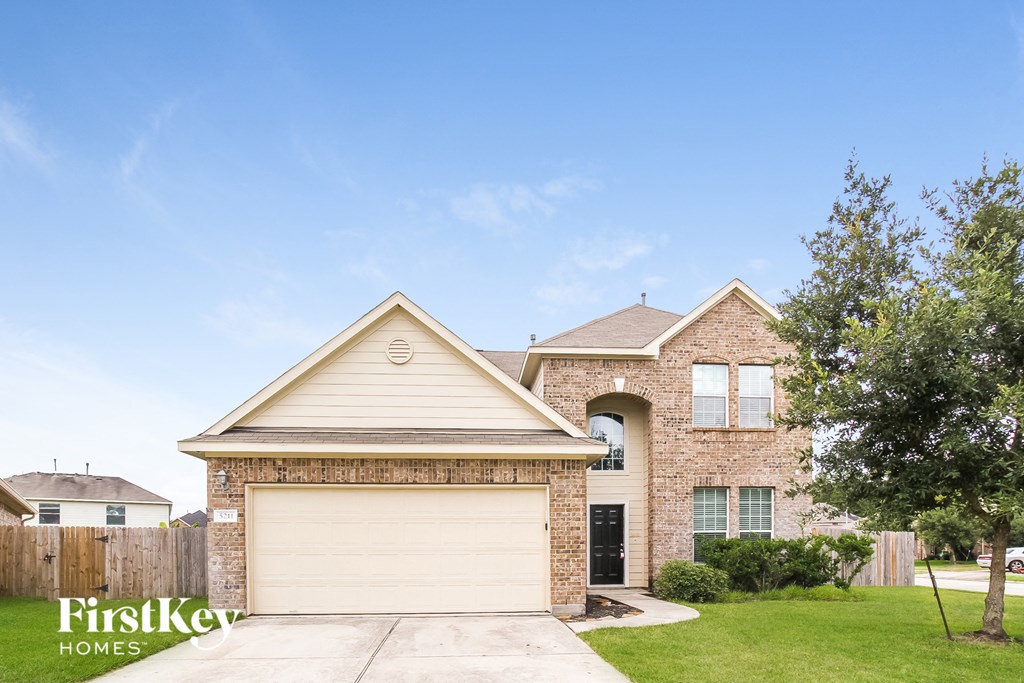 A house with a garage and a tree in front of it.