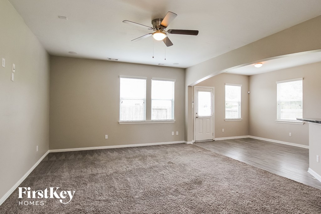 A spacious room with a carpeted floor, a ceiling fan, and a fireplace.