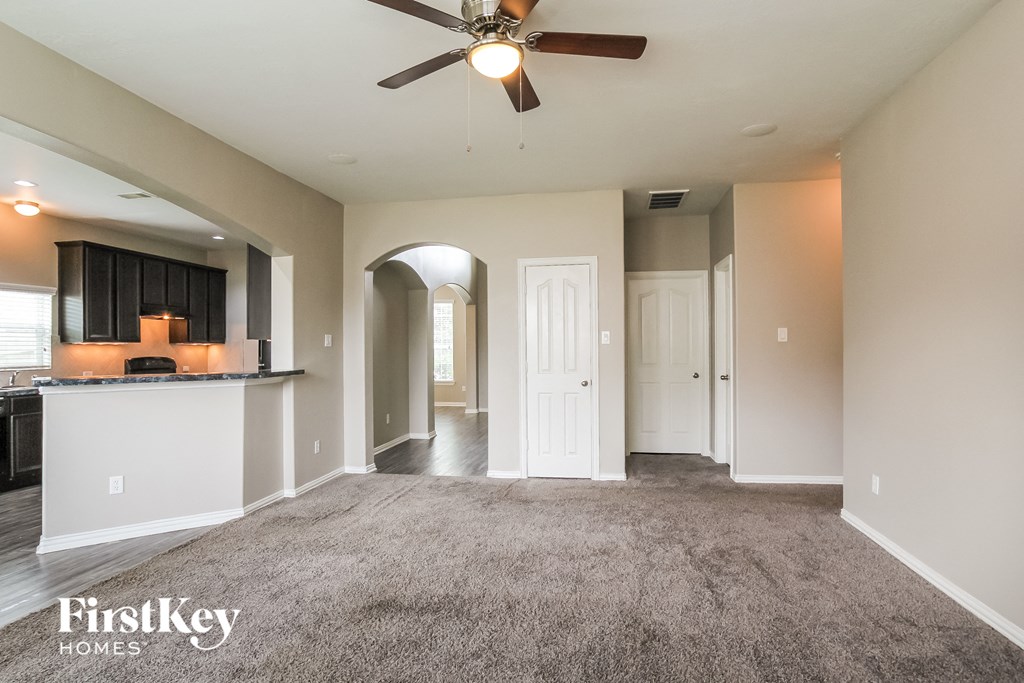 A spacious living room with a ceiling fan and a bar area.