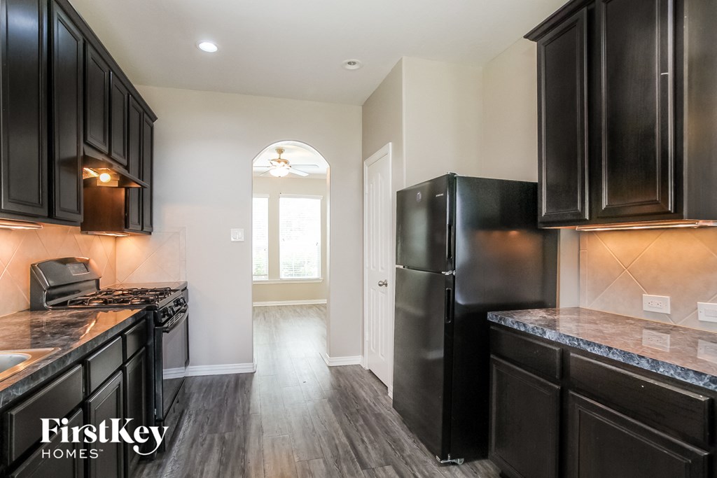 A kitchen with black cabinets and a black refrigerator.