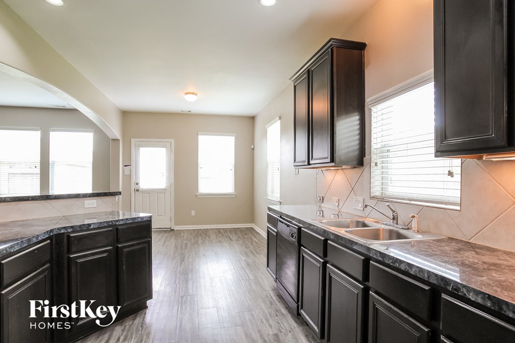 A kitchen with black cabinets and a marble countertop.